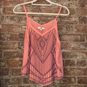 Pink flowy tank top with navy blue embroidery.
